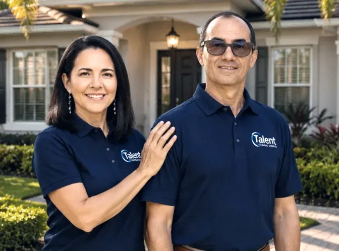 Karla Paiva and John Vicente, the owners of Talent Cleaning Services, standing together in uniform in front of a South Florida home.